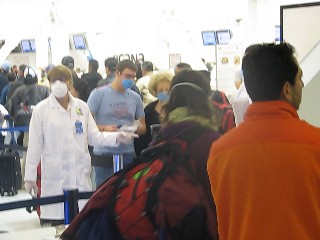 Aéroport de Mexico ce matin : un agent de la santé guide les voyageurs vers une '' scanneur'' de fièvre
