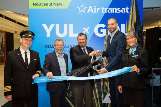 Karl Brochu, Vice-Président Exploitation et Développement aérien chez ADM Aéroports de Montréal; Victor Treviño, Consul General du Mexique à Montreal; et Bernard Côté, directeur principal, communications de marque chez Transat, entourés par des membres de l’équipage d’Air Transat.